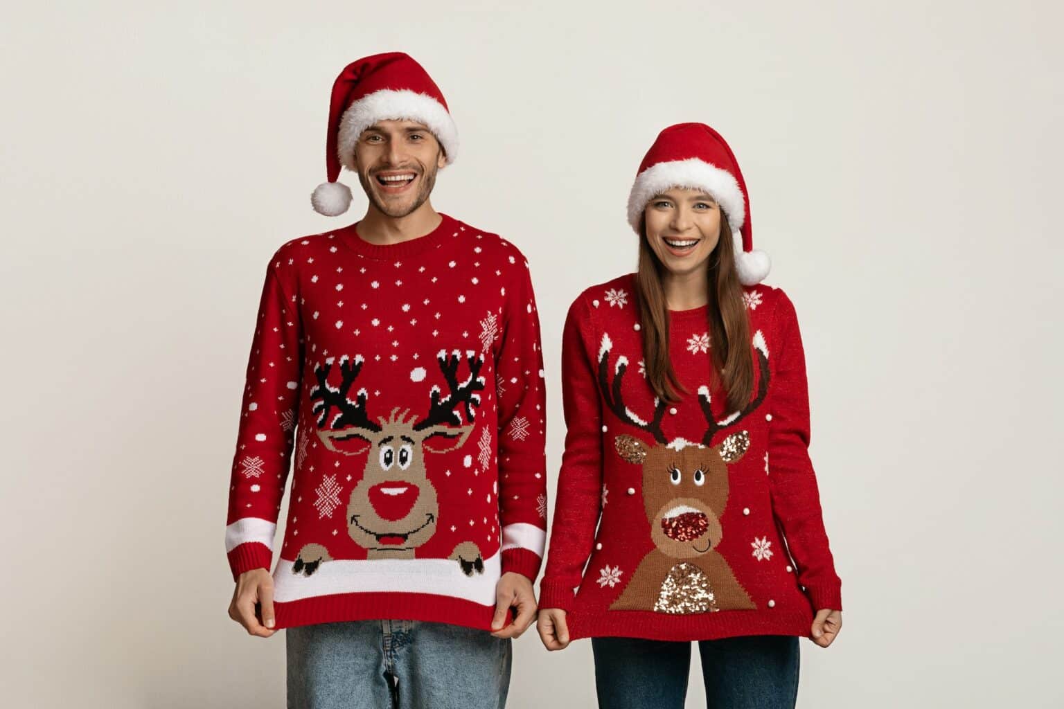 Portrait Of Funny Couple Wearing Reindeer Ugly Christmas Sweaters And Santa Hats