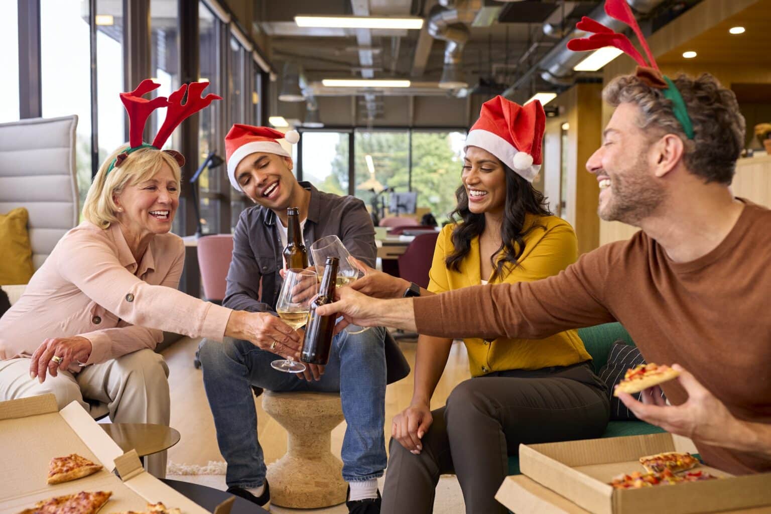 Staff Celebrating At Christmas Party With Meal And Drinks In Office