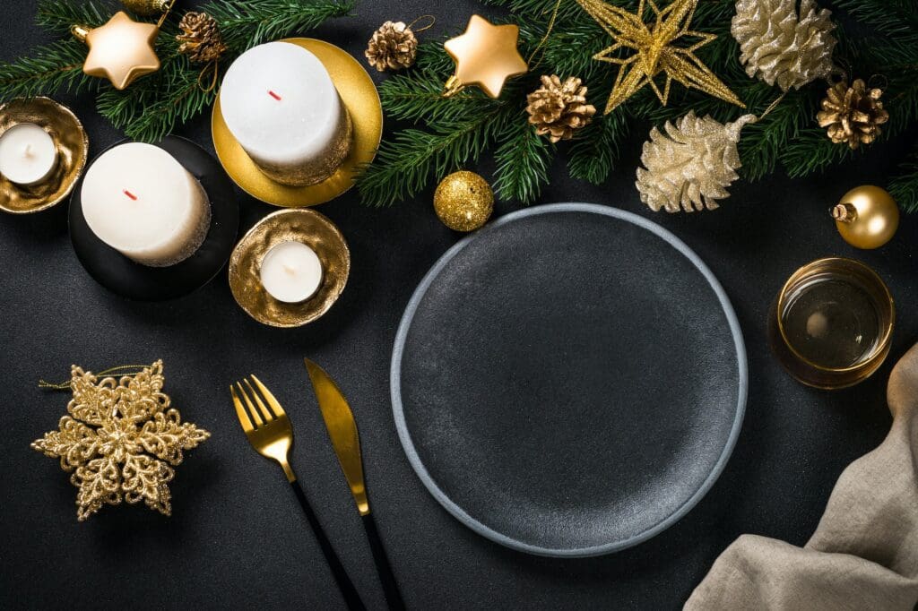 Christmas table setting with holiday decorations at black background.