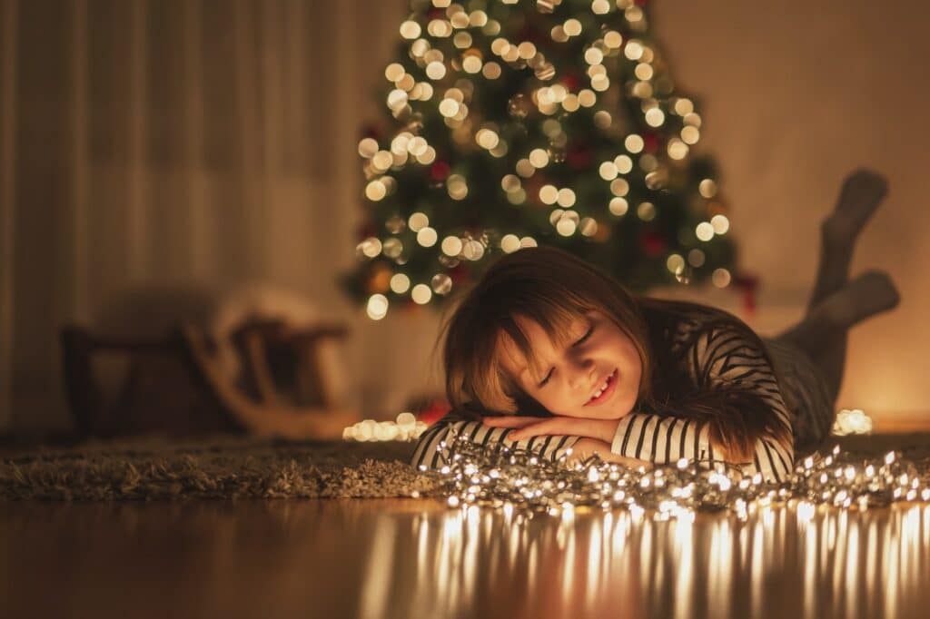 Little girl lying on the floor with bunch of Christmas lights all around